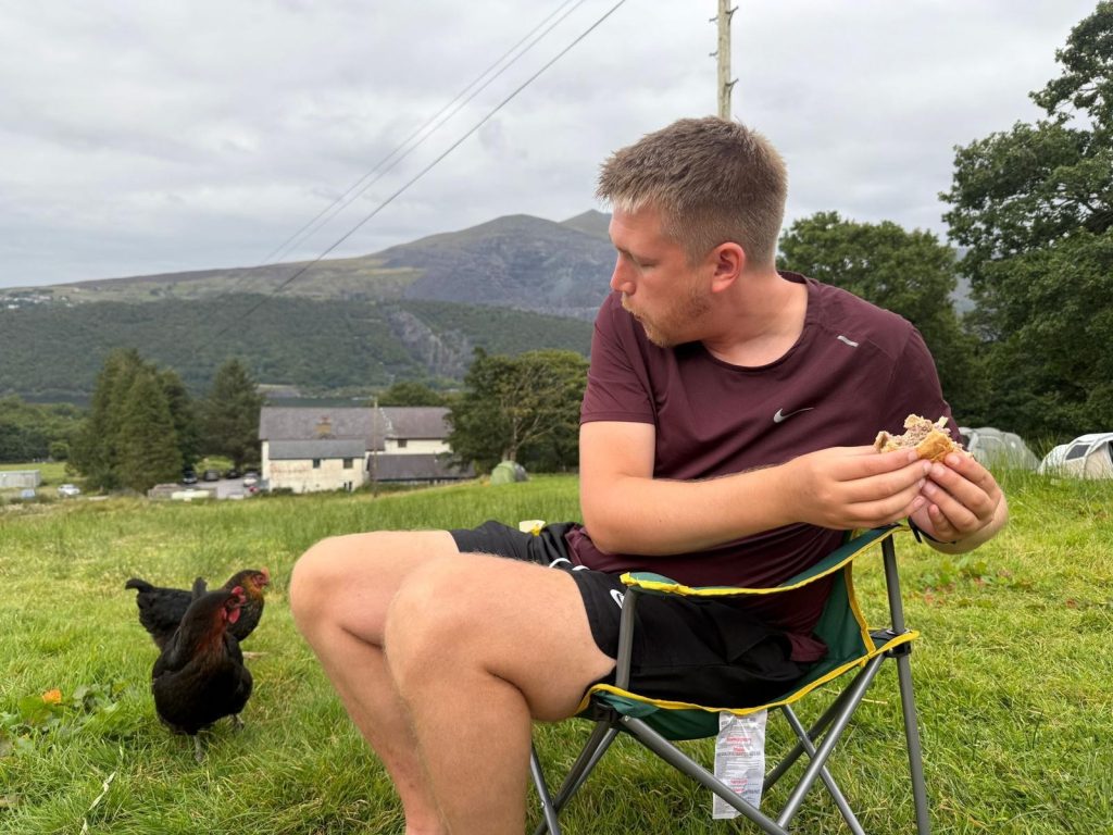 Compliance Manager, Sam Adam, fending off a hungry chicken before his training hike up Snowdon for the 3 Peaks handl Group 24 hour challenge for The Children's Society and Maggie's Centre.
